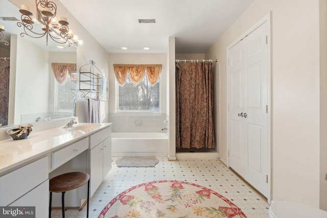 bathroom featuring vanity, a tub, and a notable chandelier