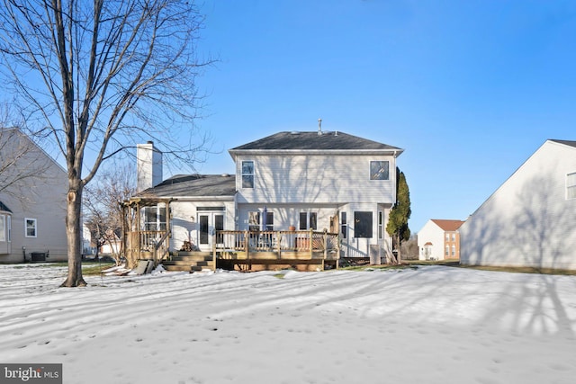 snow covered house featuring central AC unit and a wooden deck