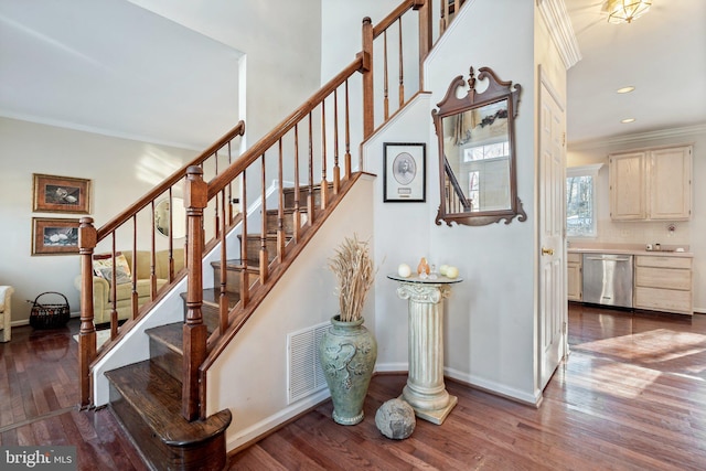 stairway with ornamental molding and wood-type flooring