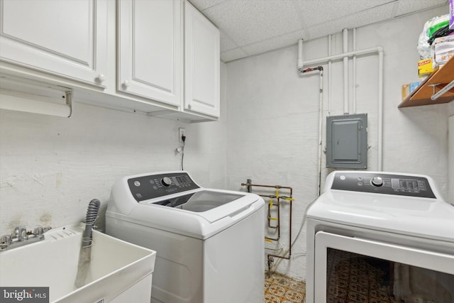 clothes washing area featuring washer and dryer, sink, electric panel, and cabinets