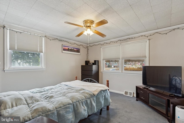 bedroom with ceiling fan, multiple windows, crown molding, and carpet flooring