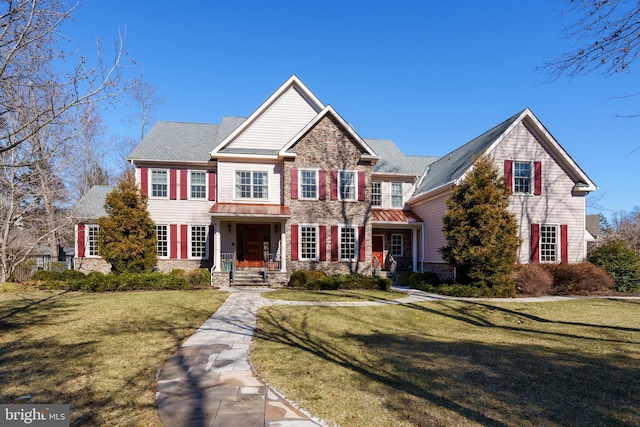 view of front of home with stone siding, a standing seam roof, metal roof, and a front yard