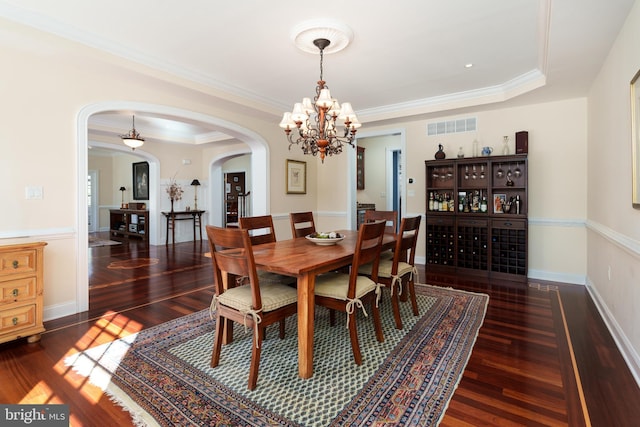 dining space featuring a tray ceiling, arched walkways, crown molding, visible vents, and wood finished floors