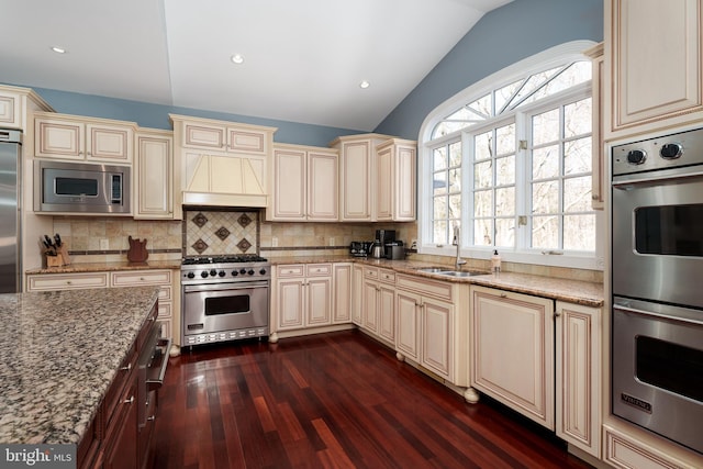 kitchen with cream cabinetry, a sink, and built in appliances