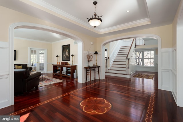 dining room featuring stairs, arched walkways, ornamental molding, and wood finished floors