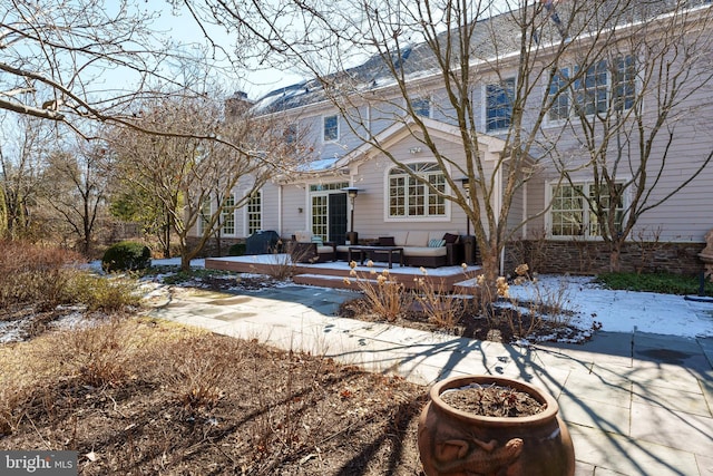 rear view of property with an outdoor living space, a patio, and a chimney