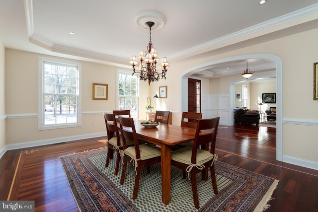 dining area featuring arched walkways, crown molding, and a tray ceiling