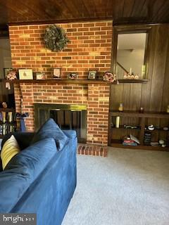 living room with wood ceiling, carpet floors, wood walls, and a fireplace