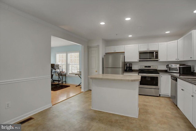 kitchen with a center island, stainless steel appliances, white cabinetry, and crown molding