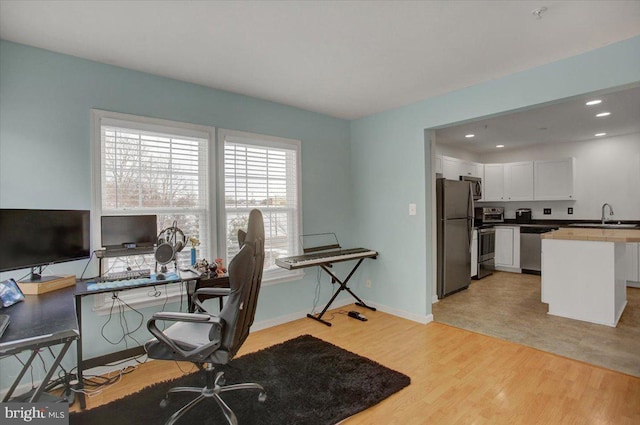 office space with light hardwood / wood-style floors and sink