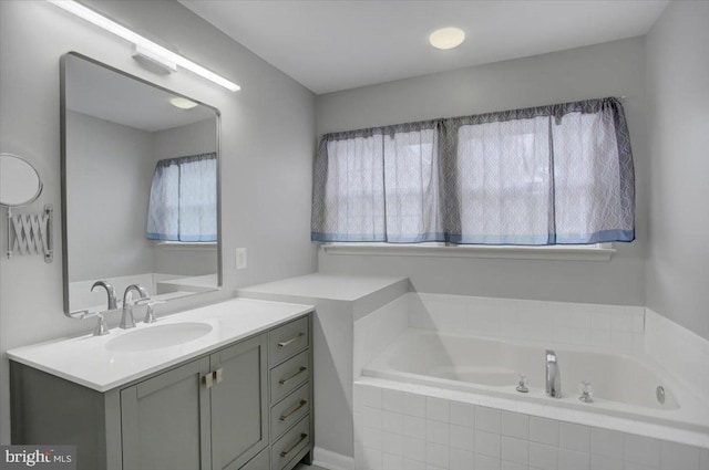 bathroom featuring vanity and tiled tub