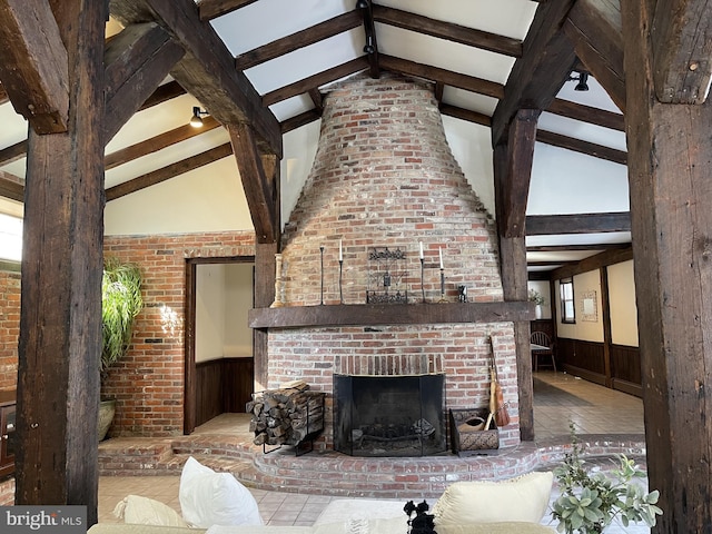 unfurnished living room featuring a fireplace, vaulted ceiling with beams, and brick wall