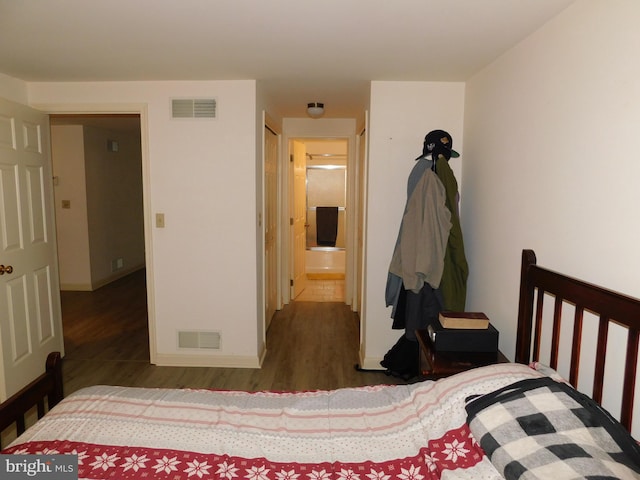 bedroom with ensuite bathroom and dark wood-type flooring