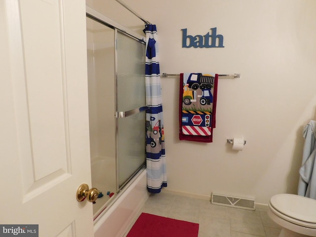 bathroom featuring combined bath / shower with glass door, tile patterned floors, and toilet