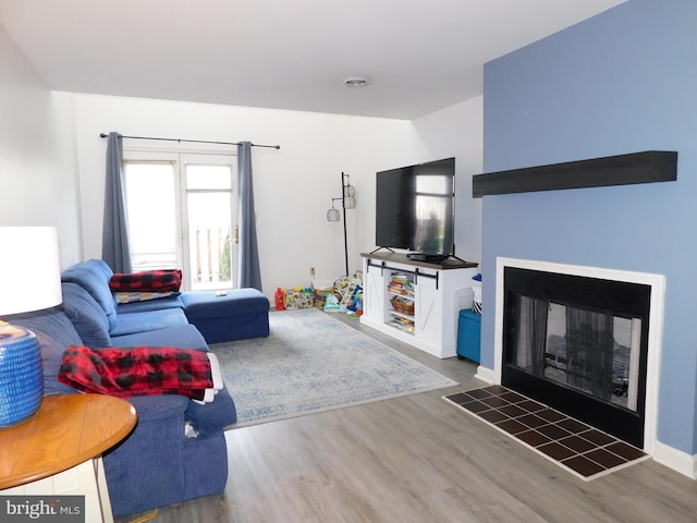 living room with a tile fireplace and hardwood / wood-style flooring