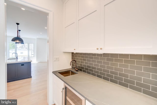 kitchen with decorative backsplash, decorative light fixtures, white cabinetry, and sink