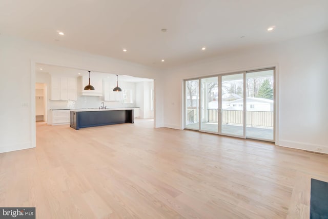 unfurnished living room featuring light wood-type flooring and sink