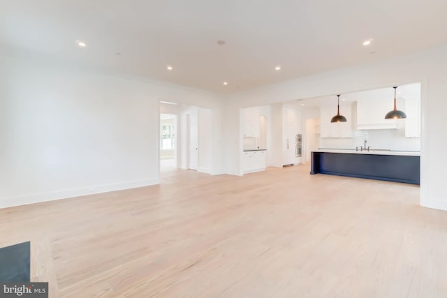 unfurnished living room with light hardwood / wood-style flooring and sink