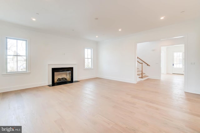 unfurnished living room featuring light hardwood / wood-style flooring, plenty of natural light, and crown molding