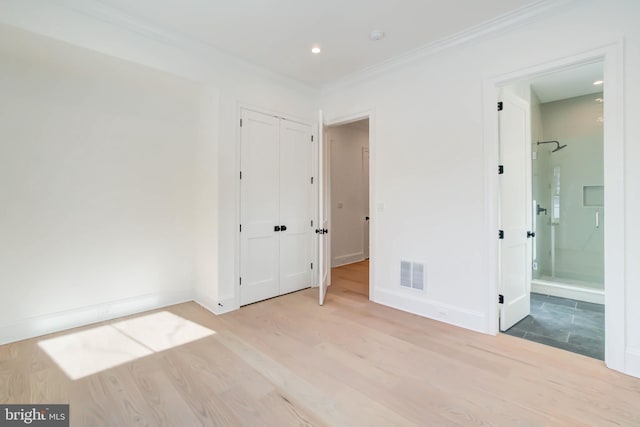 unfurnished bedroom with ensuite bath, ornamental molding, and light wood-type flooring