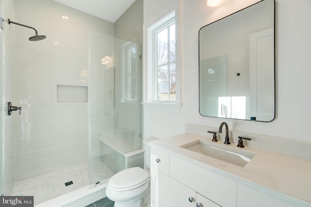 bathroom with a tile shower, vanity, and toilet