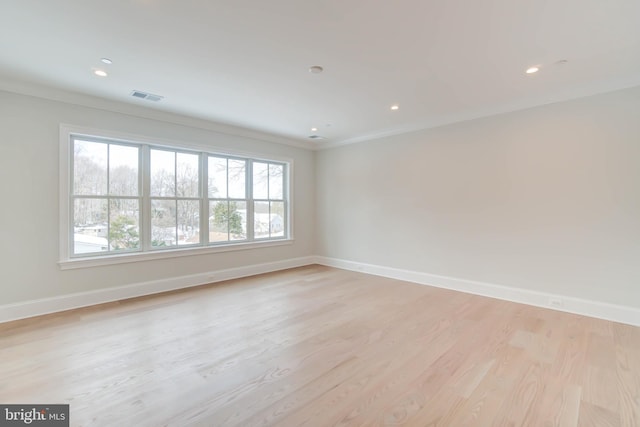 spare room featuring crown molding and light hardwood / wood-style floors