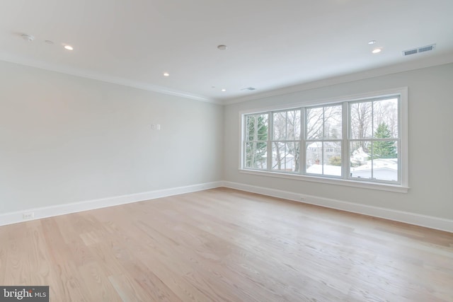 empty room featuring a healthy amount of sunlight, crown molding, and light hardwood / wood-style flooring