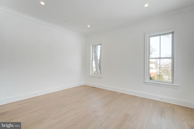 spare room featuring crown molding and light hardwood / wood-style floors