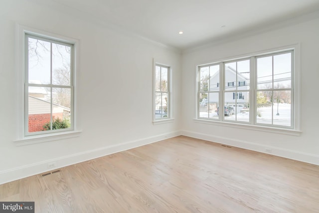 unfurnished room with light hardwood / wood-style floors, a wealth of natural light, and ornamental molding