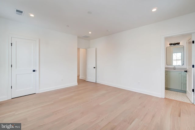 unfurnished bedroom featuring ensuite bathroom and light hardwood / wood-style floors