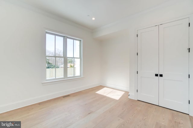 unfurnished bedroom featuring a closet, ornamental molding, and light hardwood / wood-style flooring