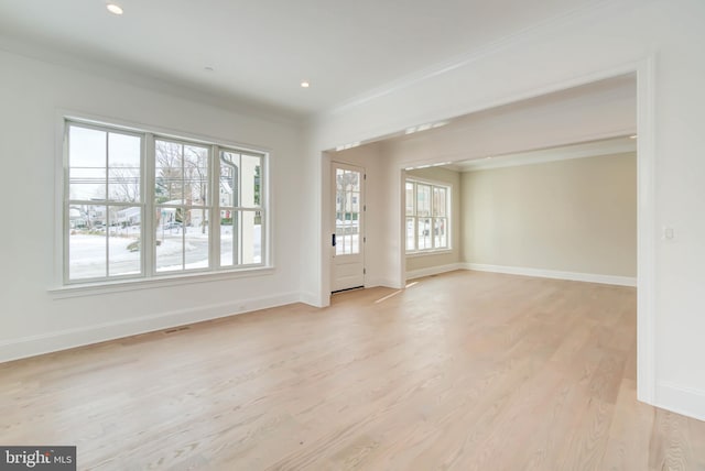 empty room with crown molding and light hardwood / wood-style floors