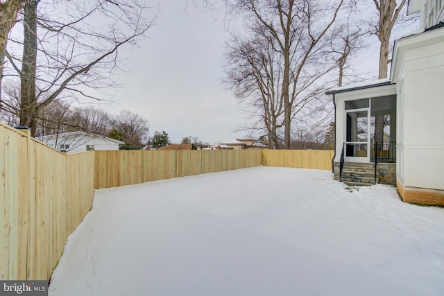 yard layered in snow with a sunroom