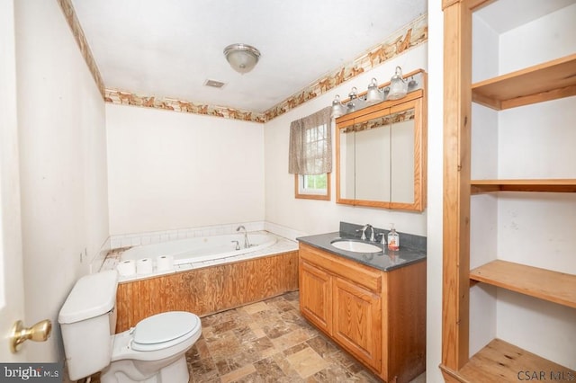 bathroom featuring vanity, a tub to relax in, and toilet