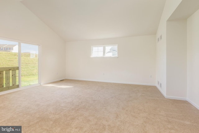 carpeted empty room with vaulted ceiling and a healthy amount of sunlight