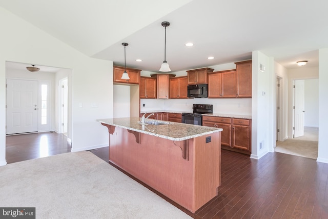 kitchen with pendant lighting, an island with sink, black appliances, a kitchen breakfast bar, and sink