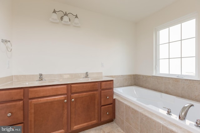 bathroom with plenty of natural light, a relaxing tiled tub, and vanity