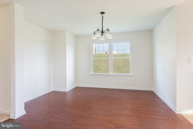 spare room with dark hardwood / wood-style floors and a chandelier