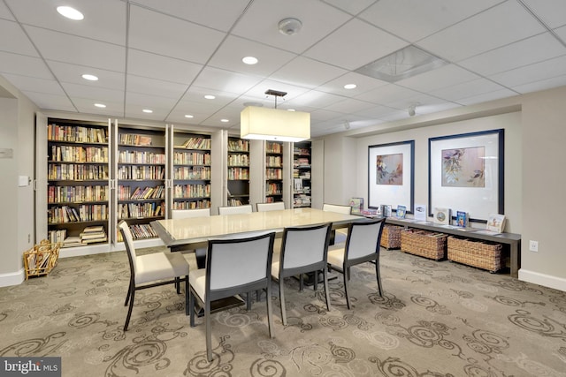 dining room with built in features, a paneled ceiling, and light carpet