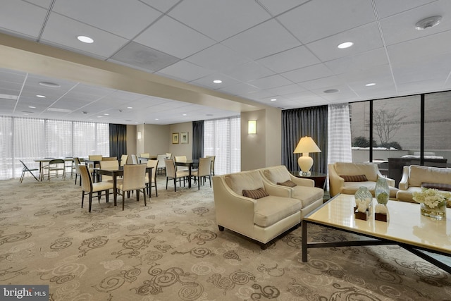 carpeted living room featuring floor to ceiling windows, a paneled ceiling, and a wealth of natural light