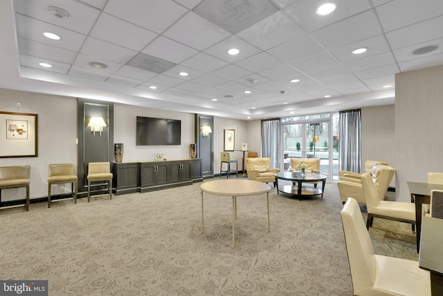 living room featuring a drop ceiling and carpet