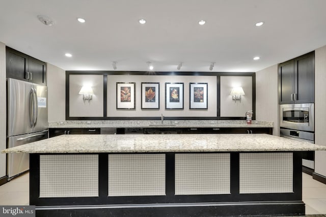 interior space featuring stainless steel appliances, light stone countertops, and a spacious island