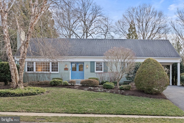 ranch-style house featuring aphalt driveway, brick siding, a front lawn, and roof with shingles