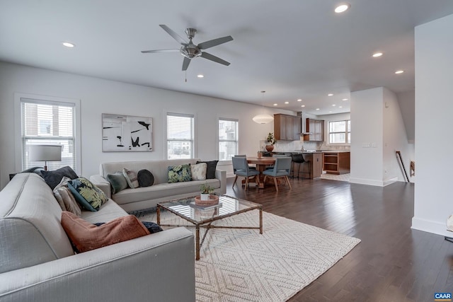 living room featuring ceiling fan, dark wood-type flooring, and plenty of natural light