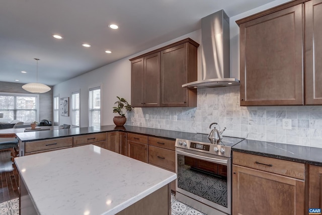 kitchen featuring stainless steel electric range, wall chimney range hood, and dark stone countertops