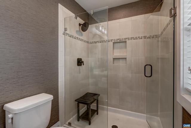 bathroom with a shower with door and toilet