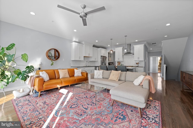 living room featuring ceiling fan, sink, and dark hardwood / wood-style flooring