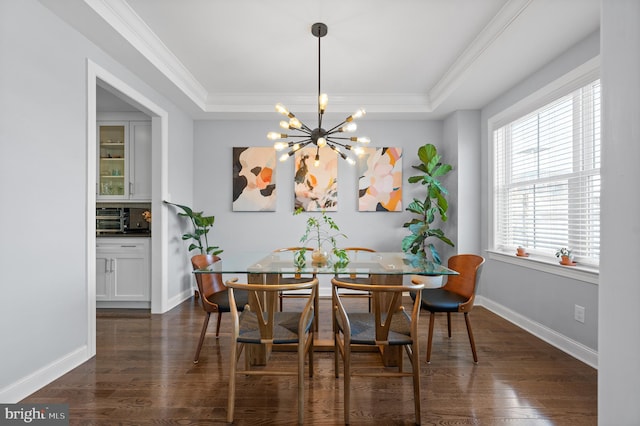 dining area with dark wood-type flooring, a tray ceiling, crown molding, and a notable chandelier