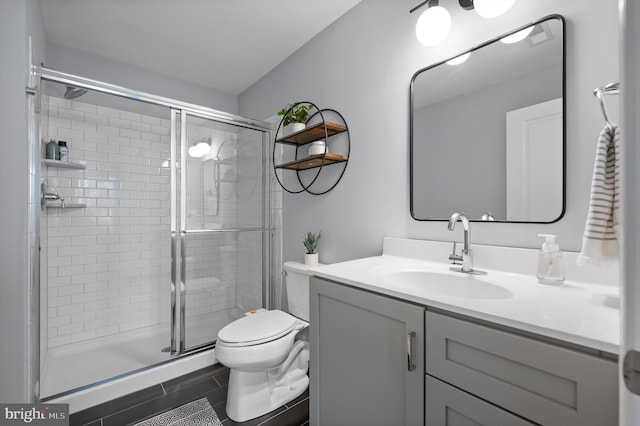 bathroom with toilet, vanity, tile patterned flooring, and a shower with shower door