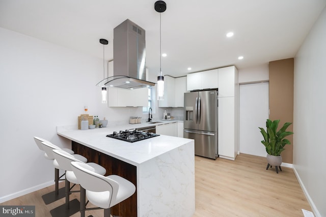 kitchen with black gas stovetop, decorative light fixtures, stainless steel fridge, island exhaust hood, and white cabinetry